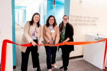 Three women cut a ribbon at an opening event