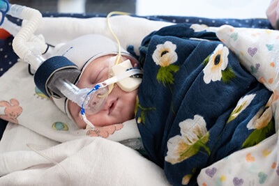 Sleeping baby in blanket wearing a mask