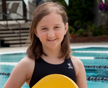 A girl in front of a swimming pool