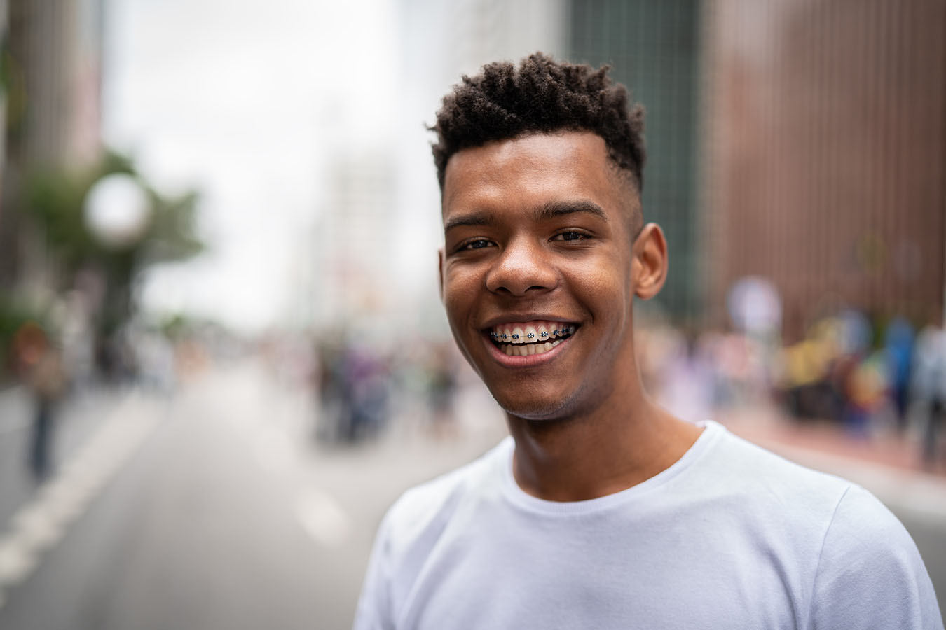 A young man stands outside and smiles at the camera.