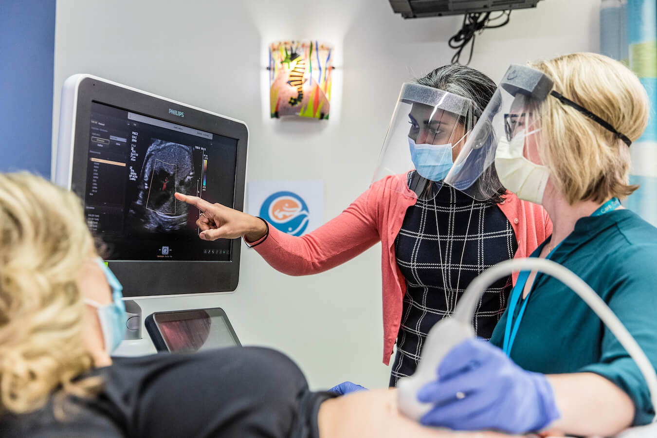 Doctor and ultrasound tech showing a patient her fetal ultrasound on screen