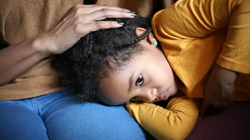 Child with a stomachache takes comfort in their parents lap.