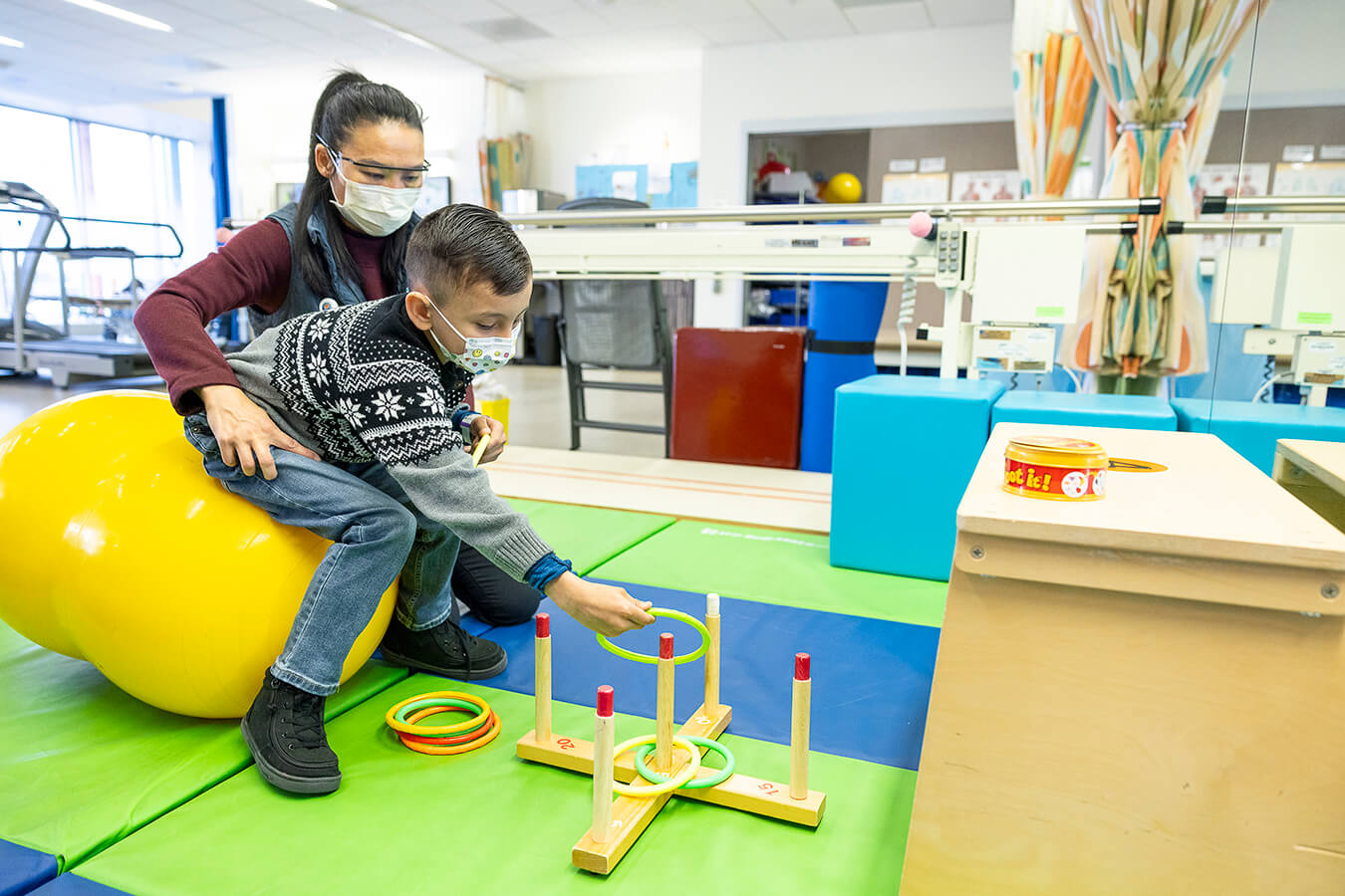 A child and a physical therapist playing with rings