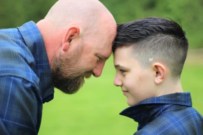 A father and son press their heads together