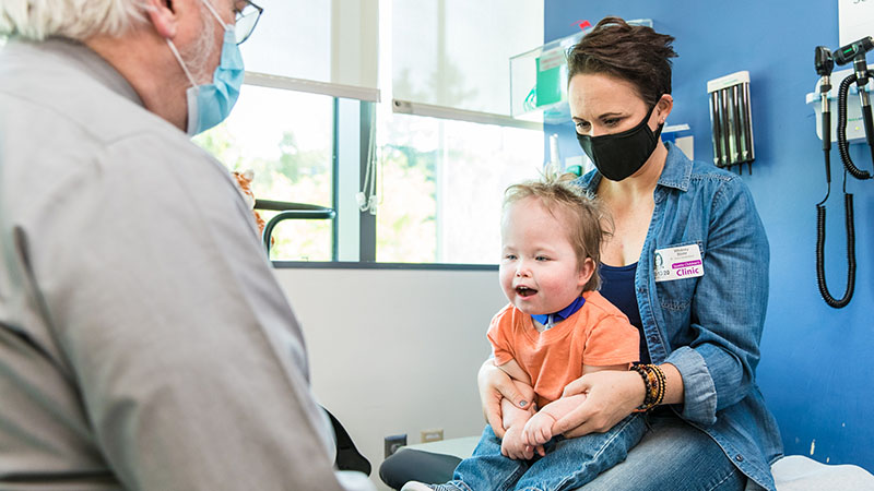 A mother holds her son in an exam room