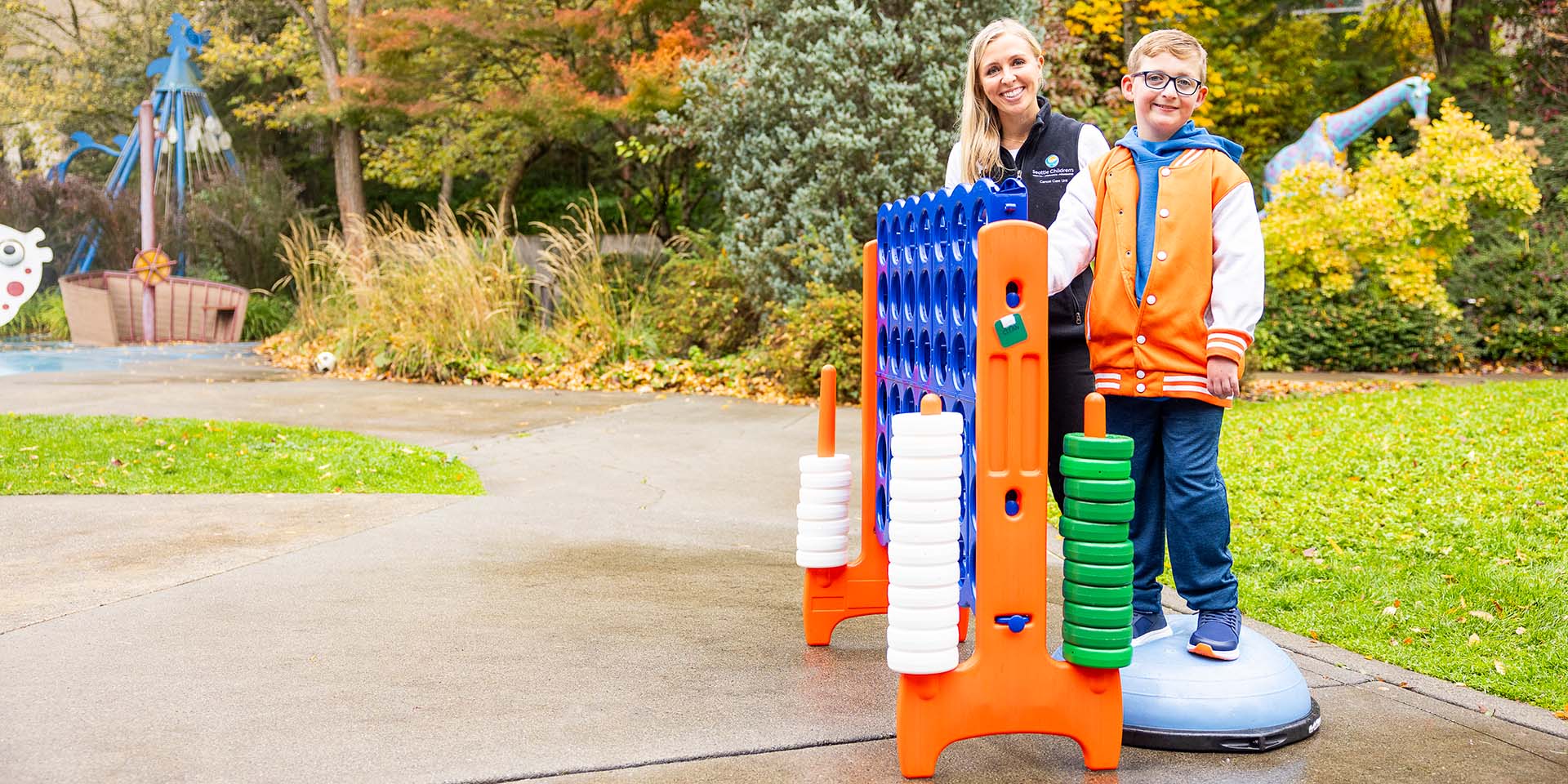 Declan and his care team member Lindsay outside playing Connect Four