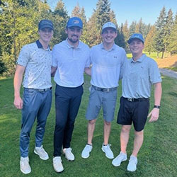 Three men pose for a picture on a golf course.