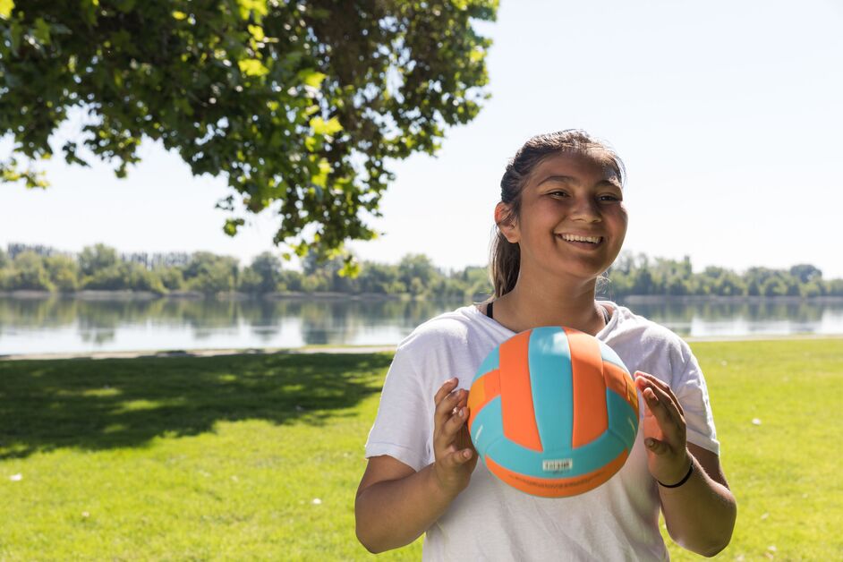 Smiling teenager holding a colorful volleyball