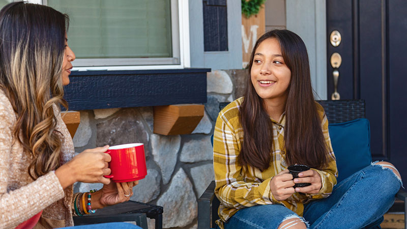 A mother and daughter chat over hot drinks