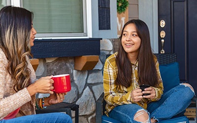 A mother and daughter chat over hot drinks