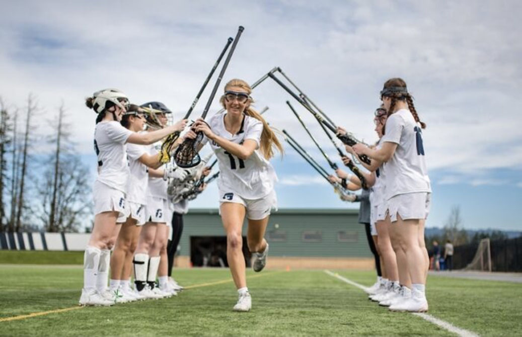 A teen lacrosse player run past her teammates