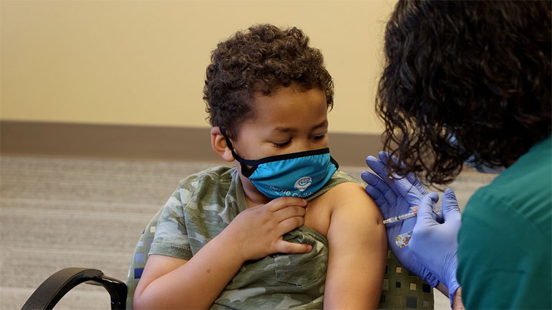 A boy with a face mask getting a vaccine