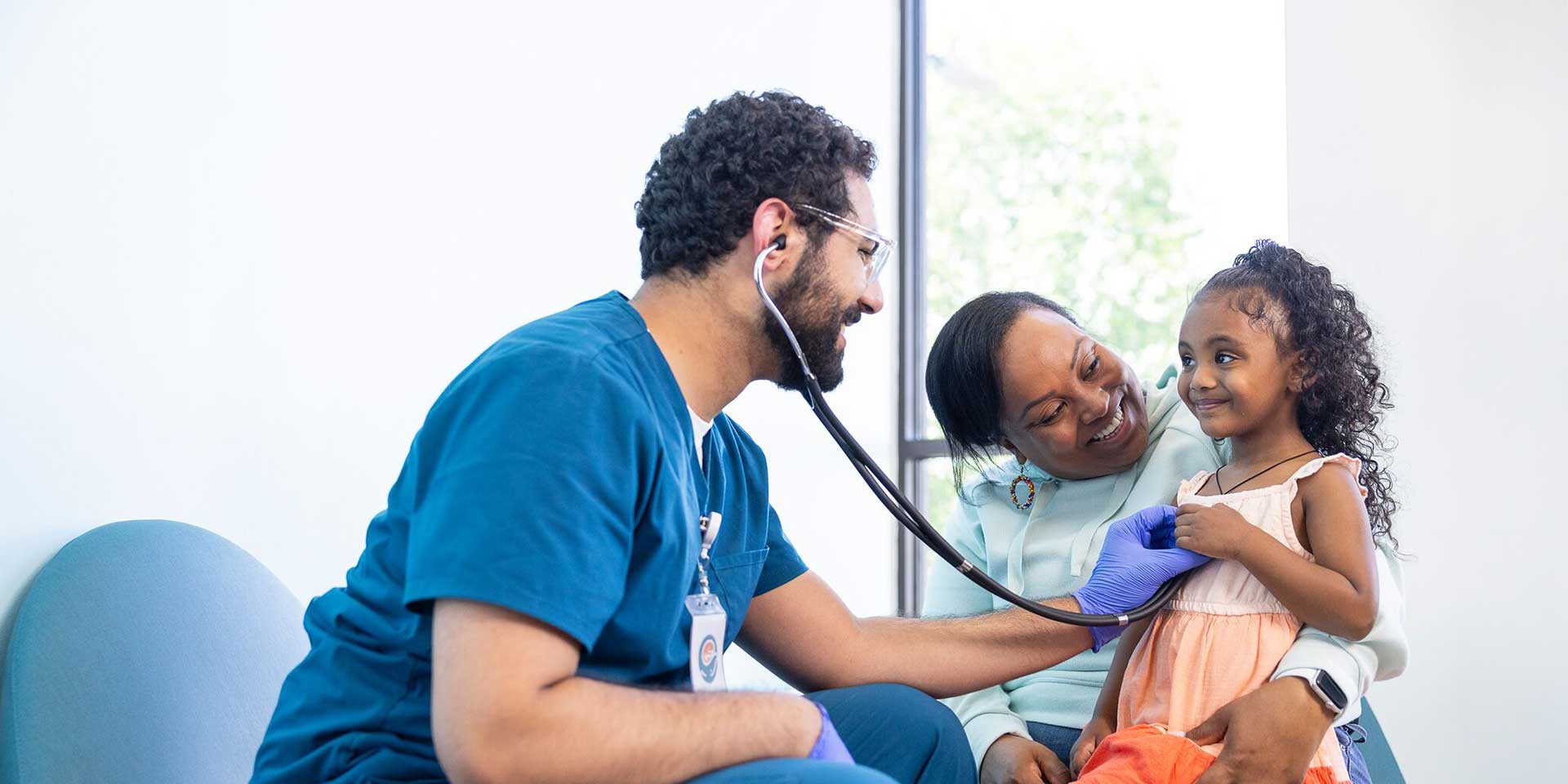 Seattle Children's doctor holds a stethoscope to a patient's heart