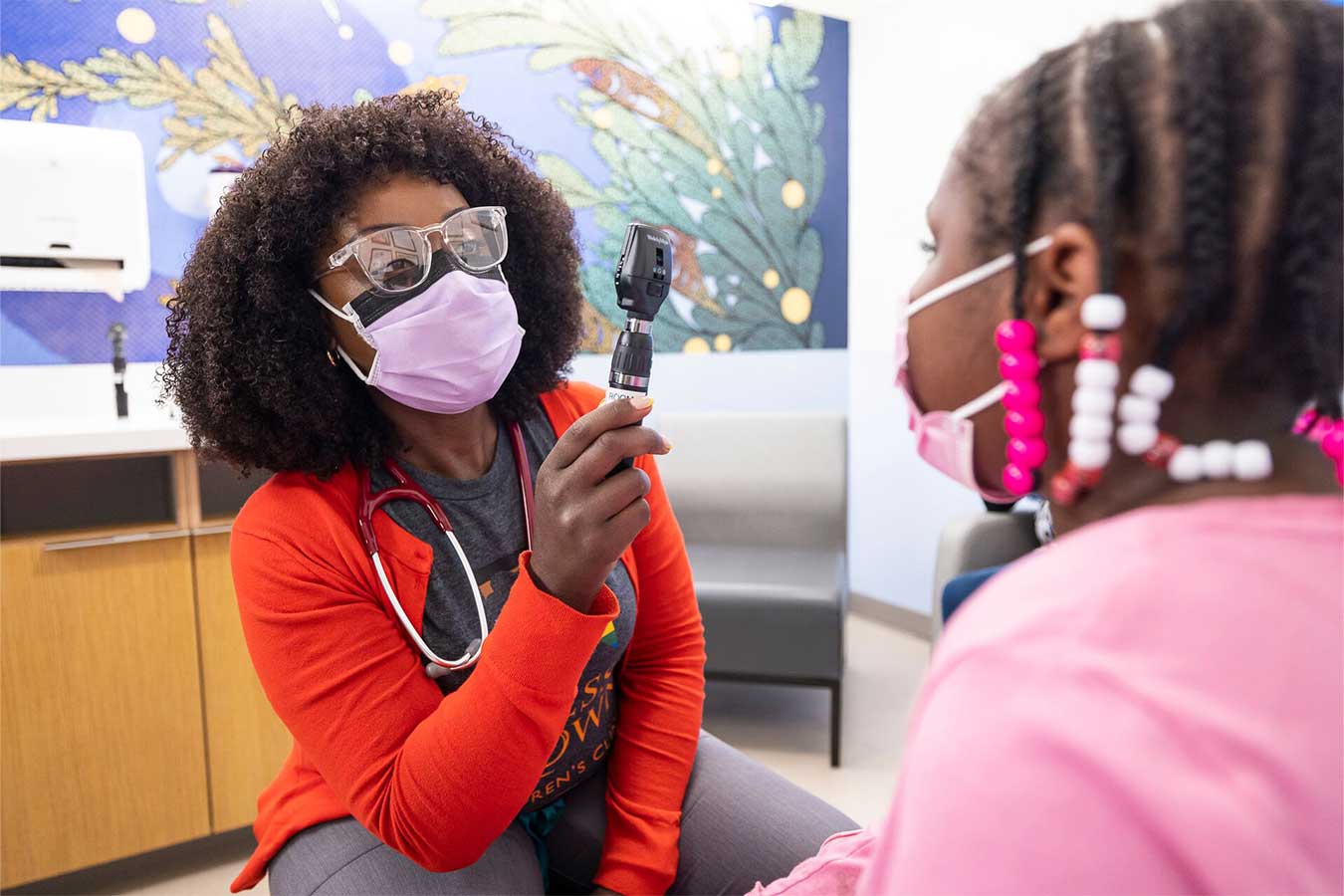 OBCC provider examines a patient in a pink sweater