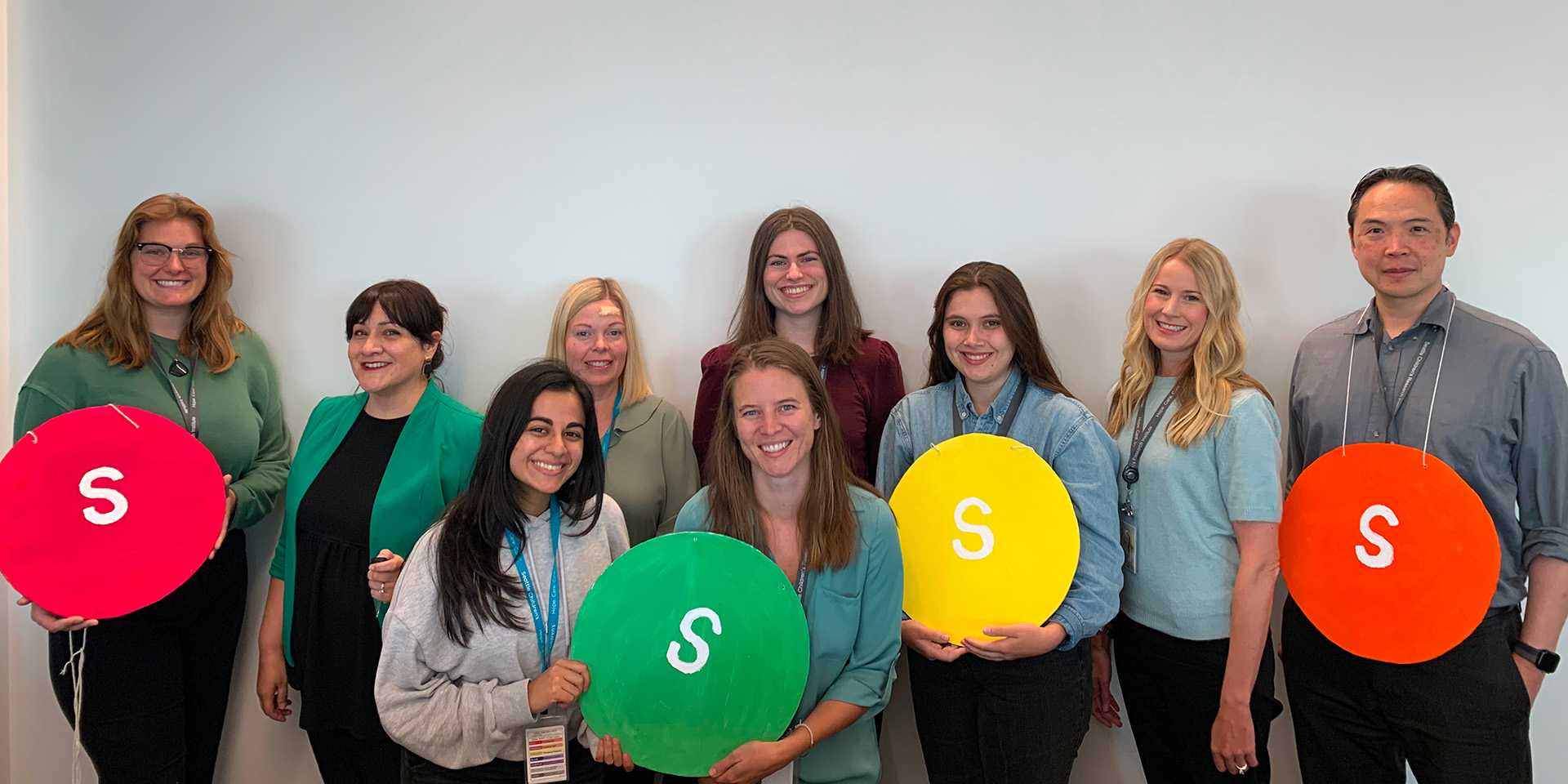 Seattle Children's researchers holding round signs with the letter S