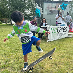 A boy plays on a skateboard in from of a Cares Foundation table