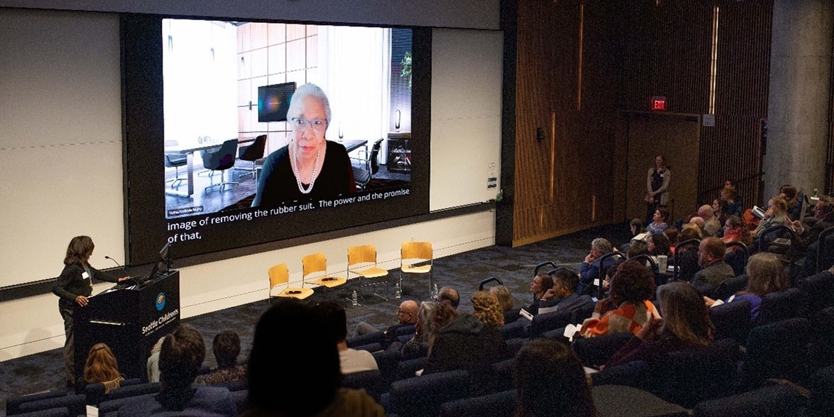 An audience watches a virtual speech